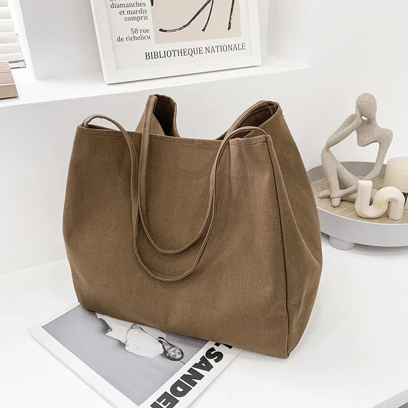 Women's black canvas shopping handbag with double shoulder straps showing internal mobile phone pocket
