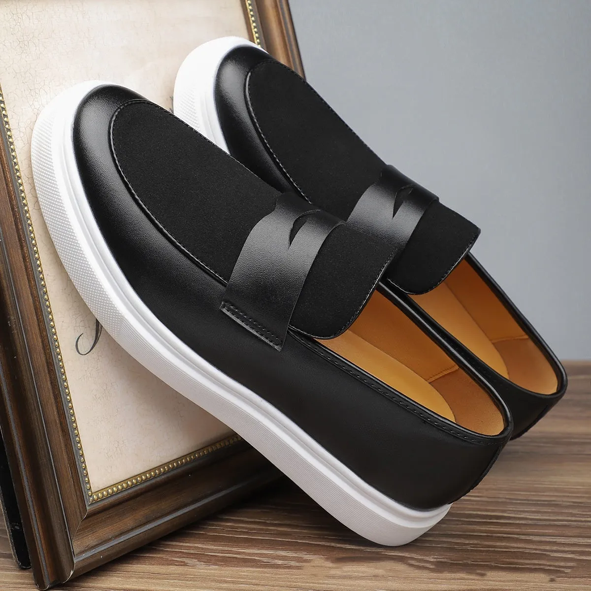 Men's black casual slip-on loafers with a tassel detail on the upper.