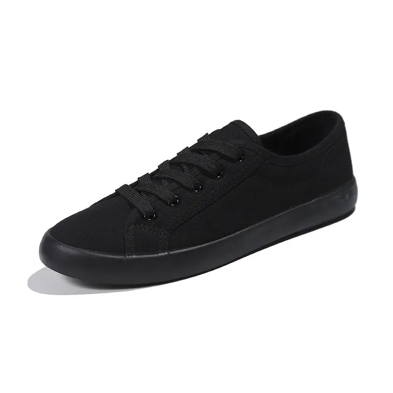 All black women's low-top canvas flat shoes with flat rubber sole and lace-up front.