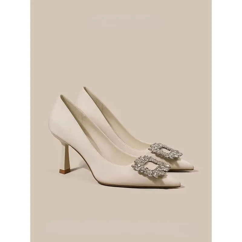 Women's creamy-white pointed toe stiletto high heels with a mid-height heel on a plain background.