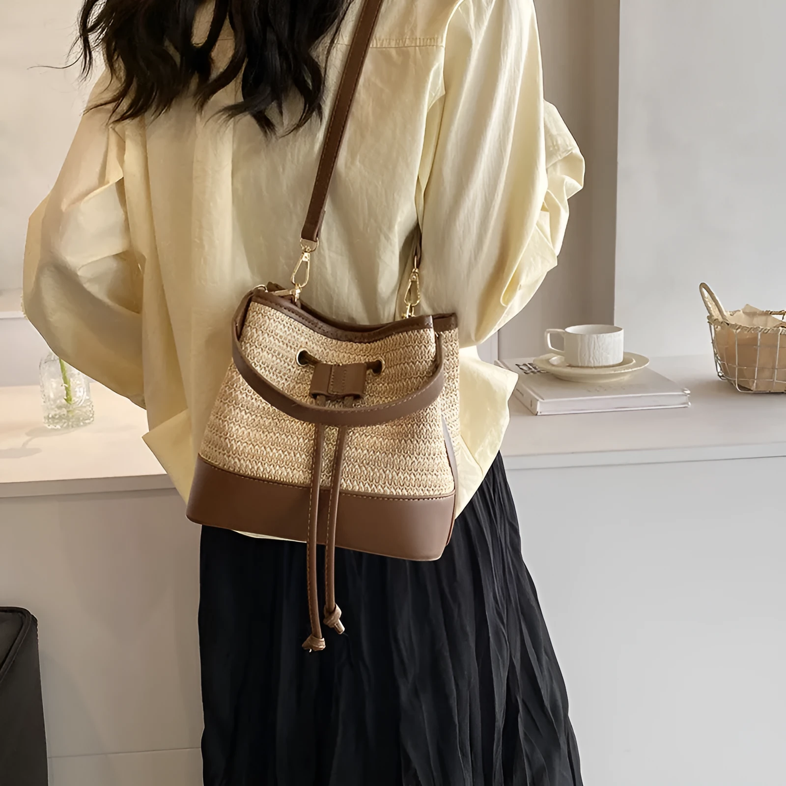 Brown woven straw women's crossbody bucket bag with a long adjustable strap.