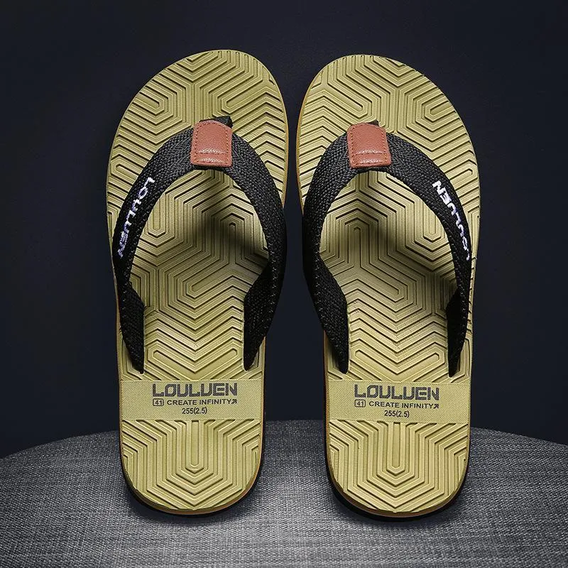 Men's black flip flops with textured non-slip sole on a beach background.