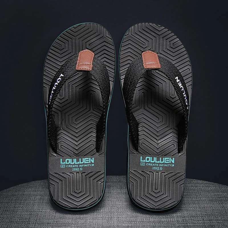 Men's black flip flops with textured non-slip sole on a beach background.