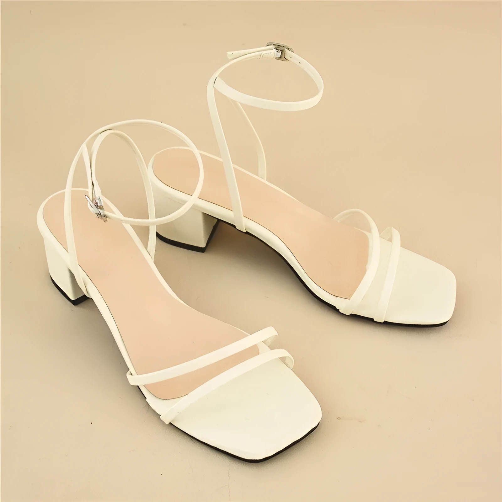 Beige women's sandals with a chunky stiletto heel, square toe, and adjustable ankle buckle on a white background.