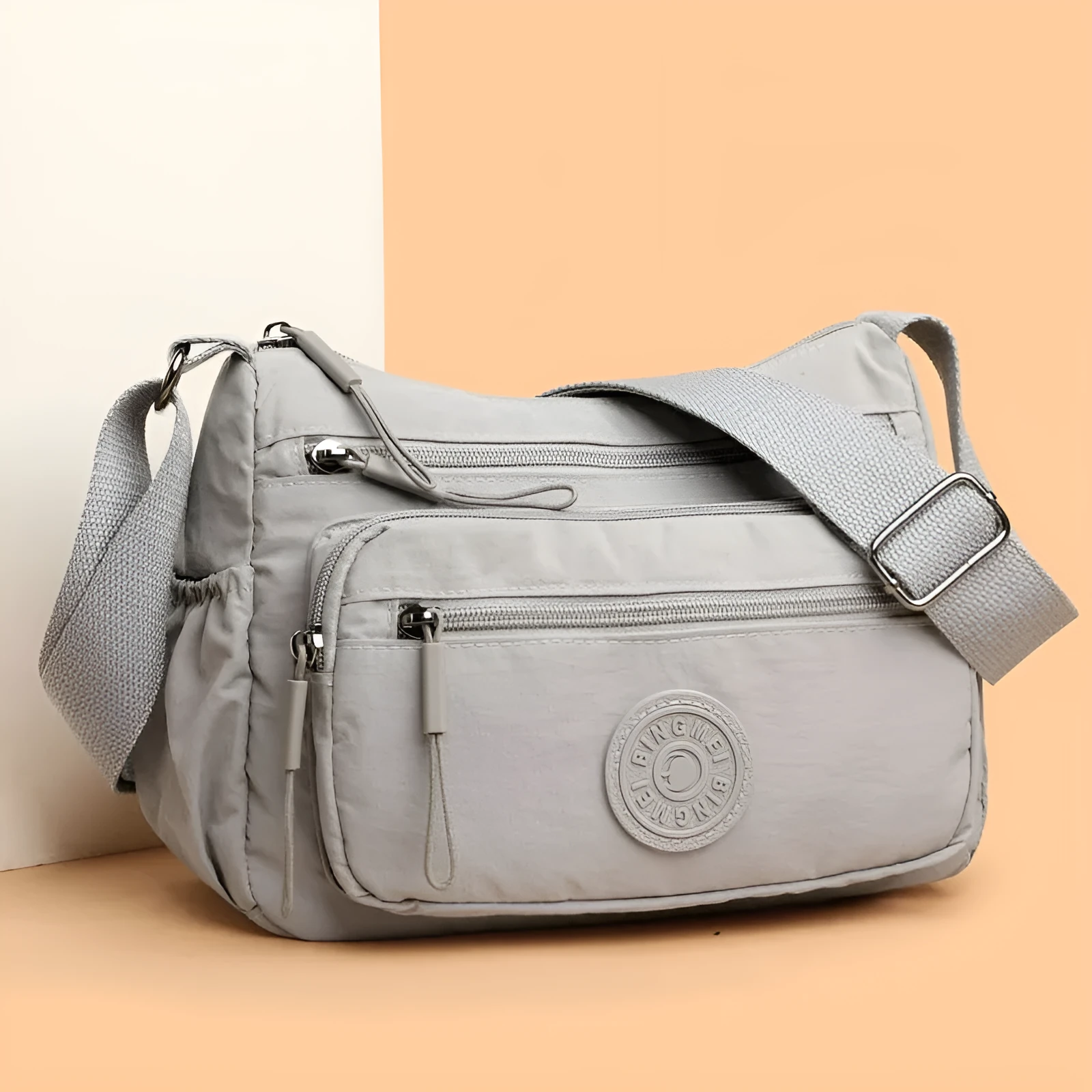 Soft water-repellent nylon crossbody bag in black, grey, or red, showing interior zipper pockets and an exterior 3D pocket.