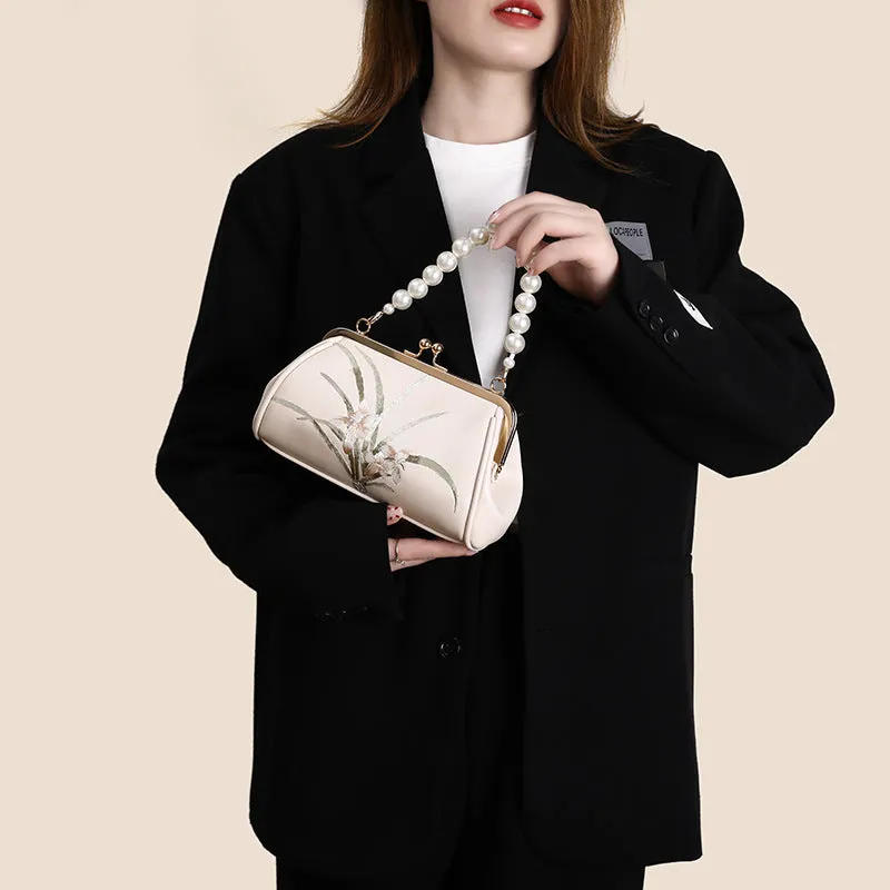 Beige women's shoulder bag with embroidered detailing and a soft, shell-shaped design.