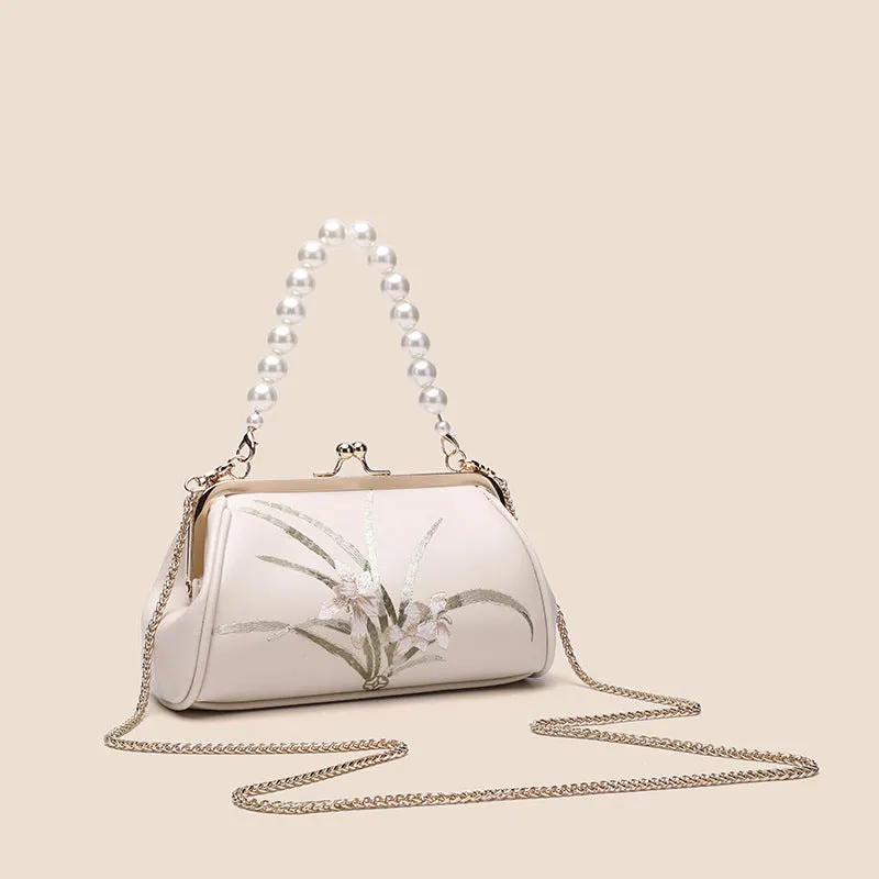 Beige women's shoulder bag with embroidered detailing and a soft, shell-shaped design.