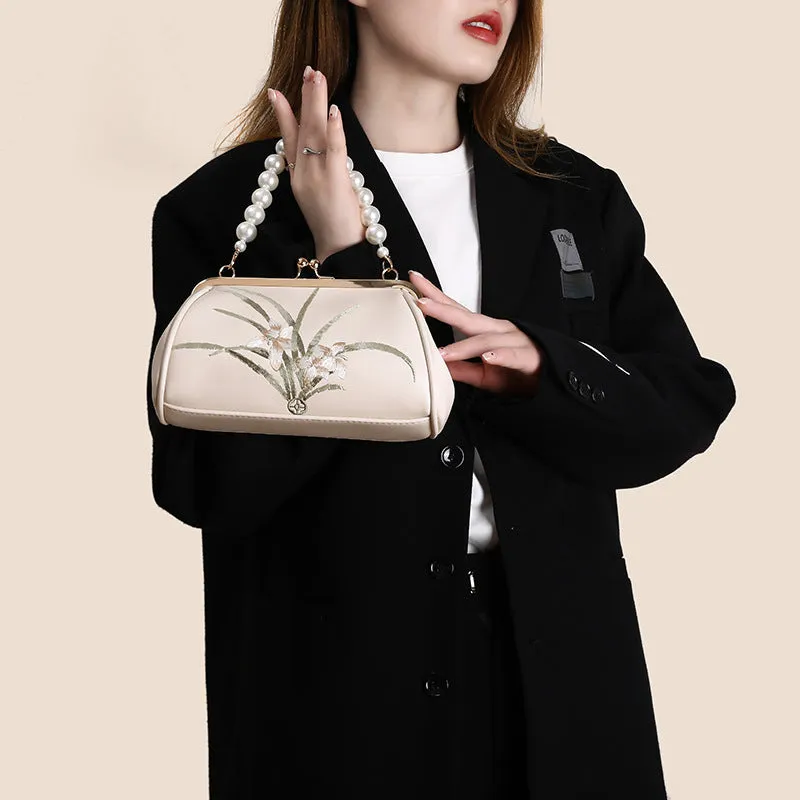 Beige women's shoulder bag with embroidered detailing and a soft, shell-shaped design.