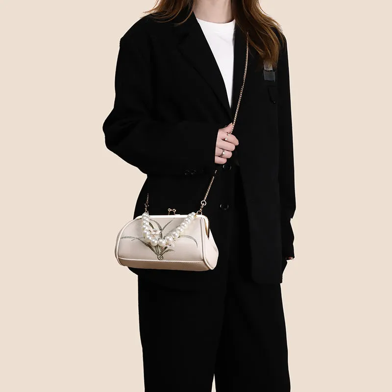 Beige women's shoulder bag with embroidered detailing and a soft, shell-shaped design.