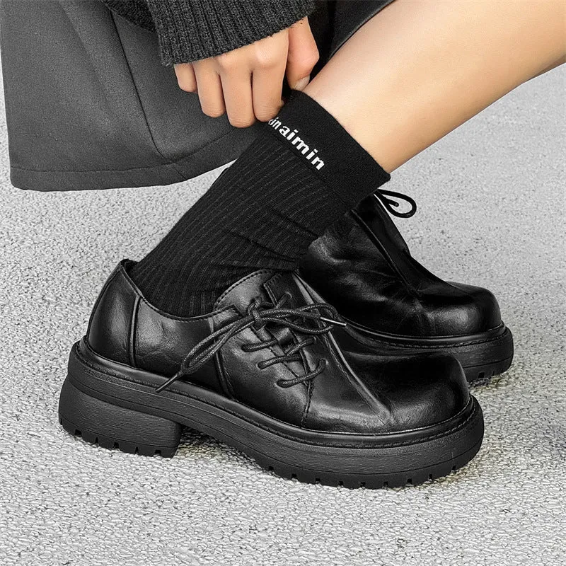Black leather platform shoes with a warped head design and round toe on a rubber sole.