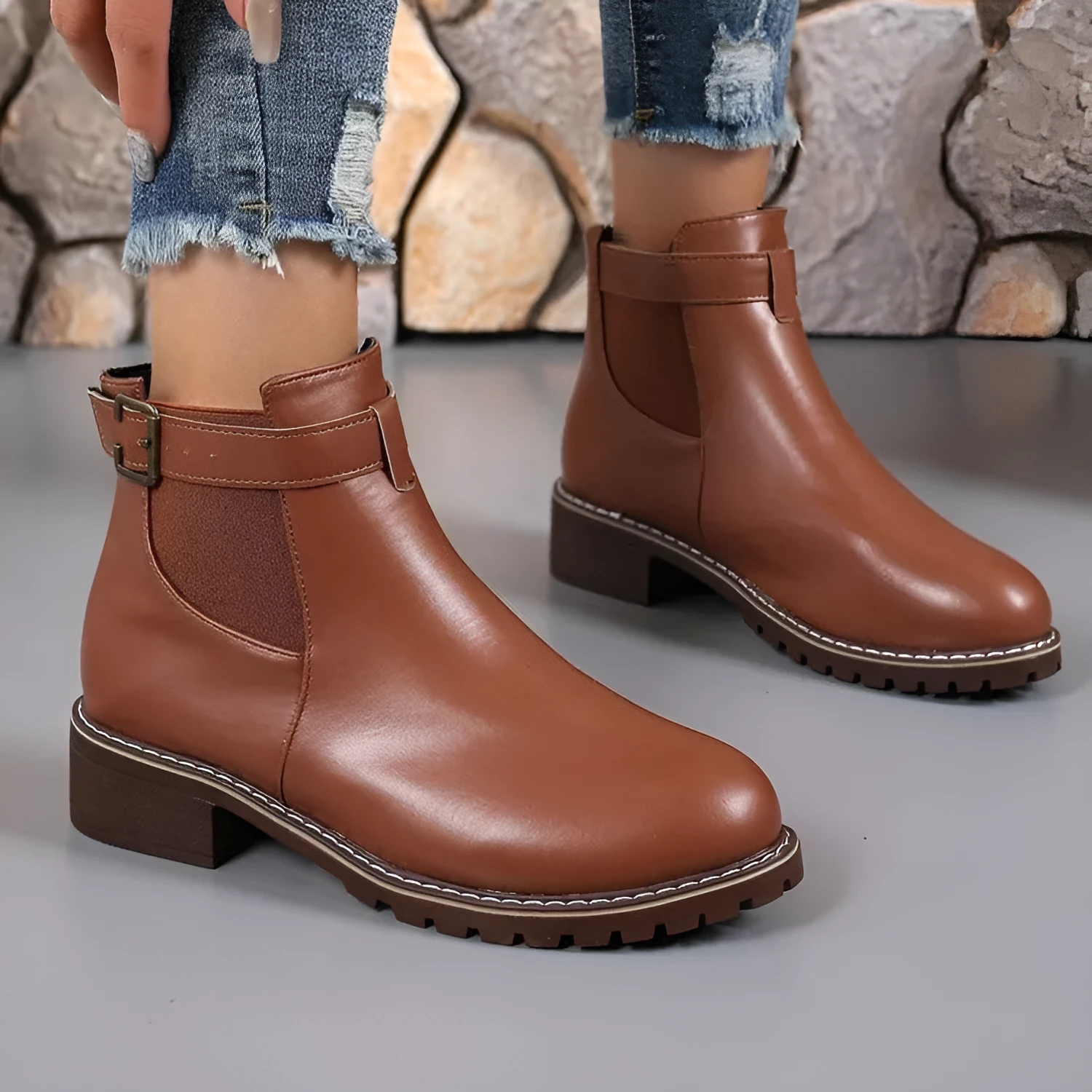 Black ankle boots with round toe and belt buckle decoration, showing rubber sole and waterproof artificial PU upper
