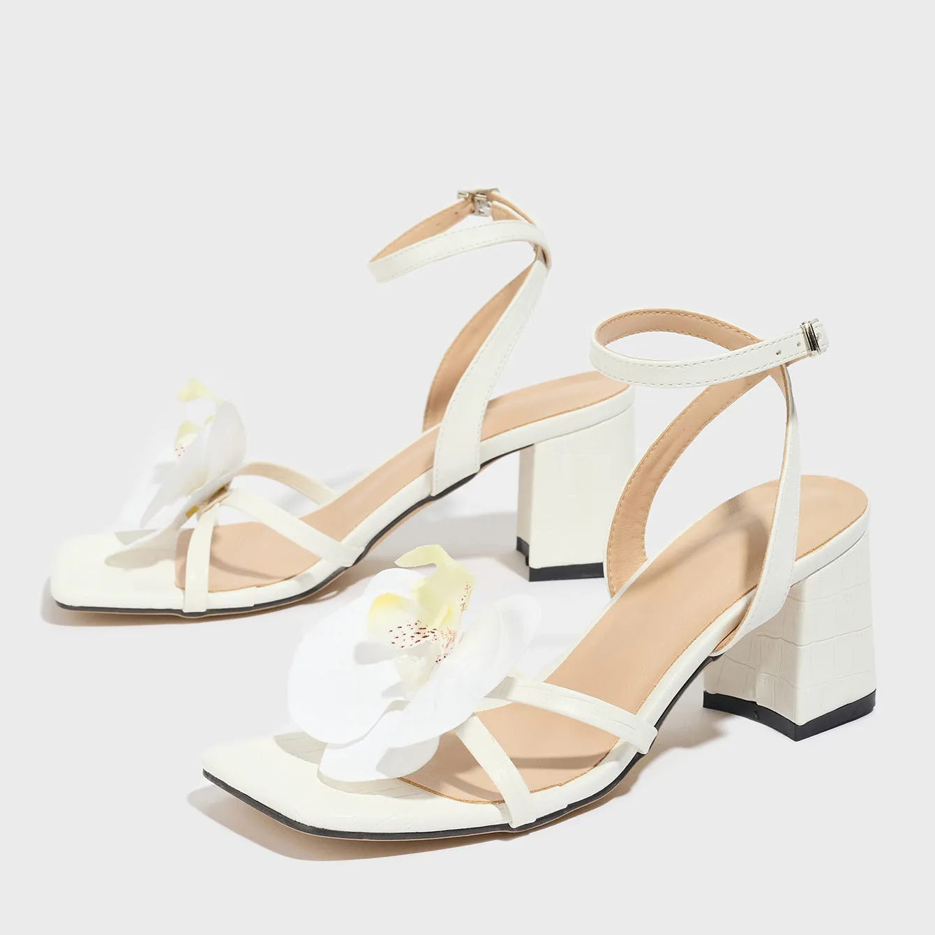 White women's sandals with a square toe, chunky high heel, and three-dimensional flower decorations.