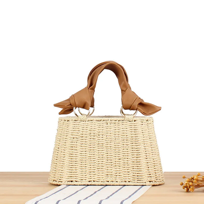 Portable woven straw bag in beige with hard trapezoid shape and double shoulder straps for seaside vacation daily use.