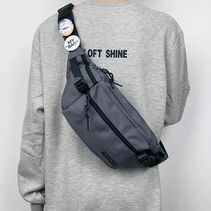 Trendy chest bag for men in Oxford cloth with letter pattern, adjustable strap, and two random badges on a plain background