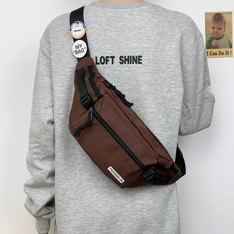 Trendy chest bag for men in Oxford cloth with letter pattern, adjustable strap, and two random badges on a plain background