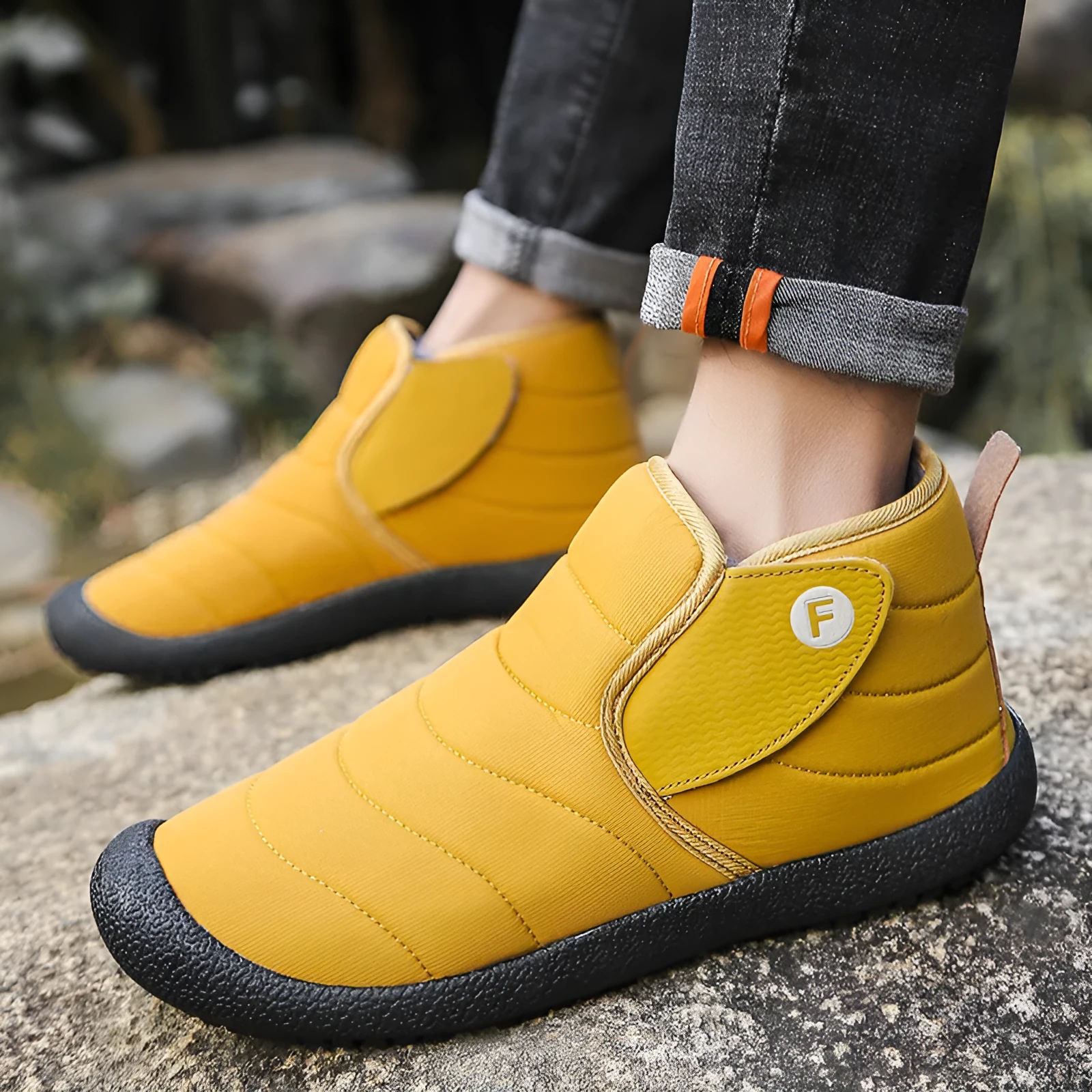 Men's thick black waterproof snow boots with a rubber sole on a hard surface.