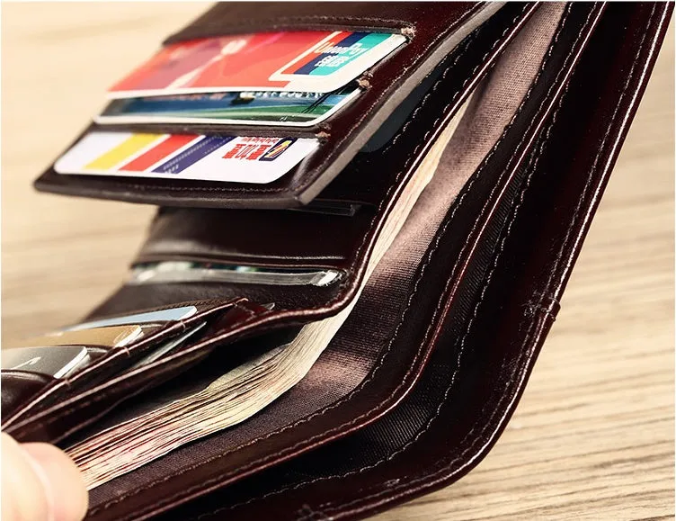 Men's black full-grain leather bifold wallet open, showing card slots, zip coin pocket, and banknote section.