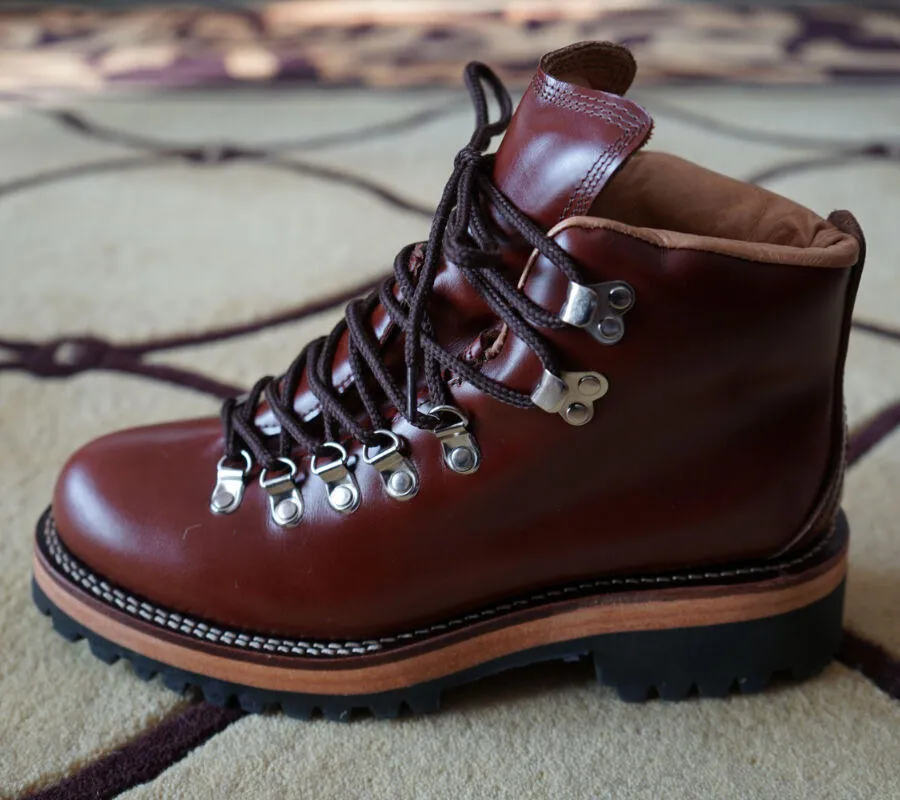 Men's brown leather city hiking boots with lace-up closure on a wooden surface