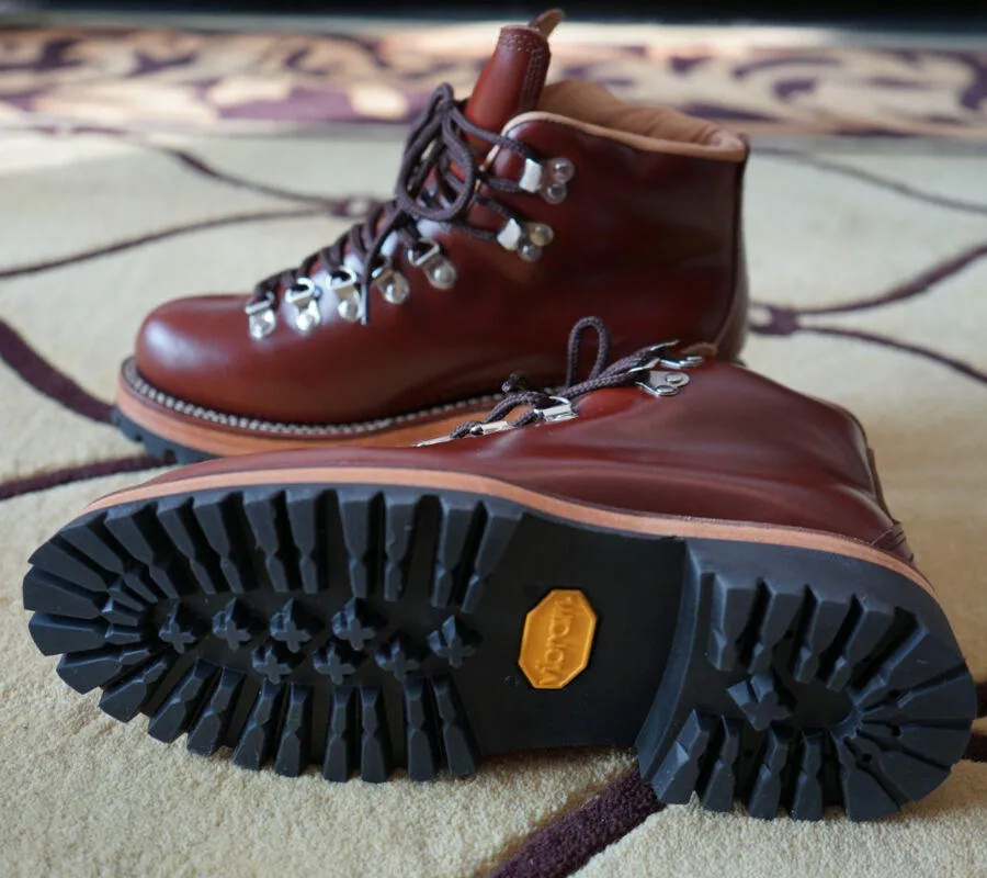 Men's brown leather city hiking boots with lace-up closure on a wooden surface