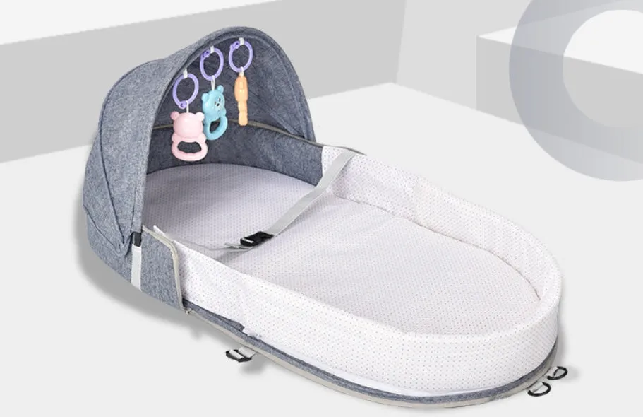 Portable foldable baby anti-mosquito isolation bed with grey cotton linen fabric, open on a grassy area