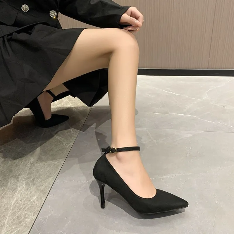 Women's black stiletto heel pumps with skull pattern and buckle detail on wooden floor