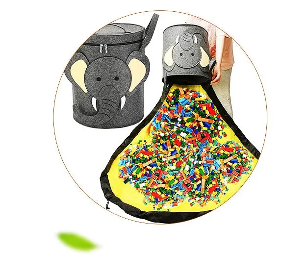 Green felt cube storage bag with pull rope, laid flat as a play mat next to toys.