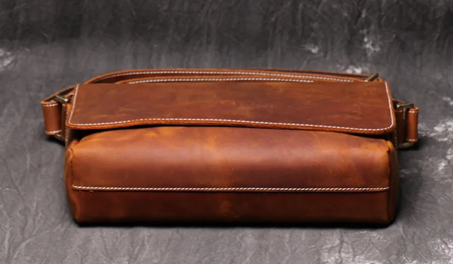 Vintage brown cowhide men's messenger bag showing front flap and adjustable shoulder strap