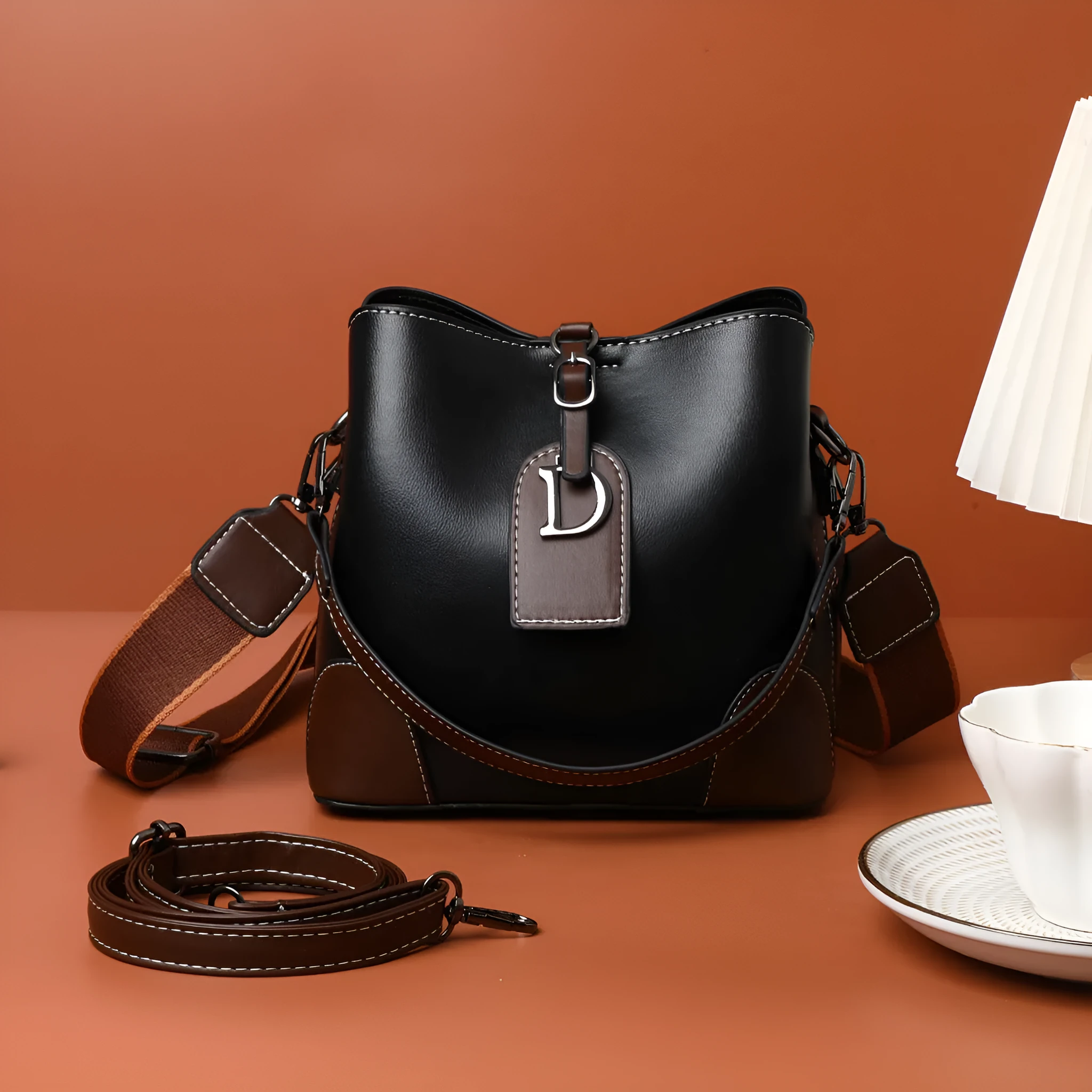 Women's soft PU bucket bag with tassel and contrast colour stitching on a plain background
