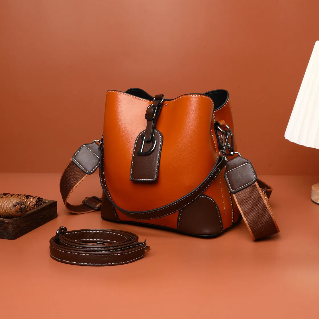 Women's soft PU bucket bag with tassel and contrast colour stitching on a plain background