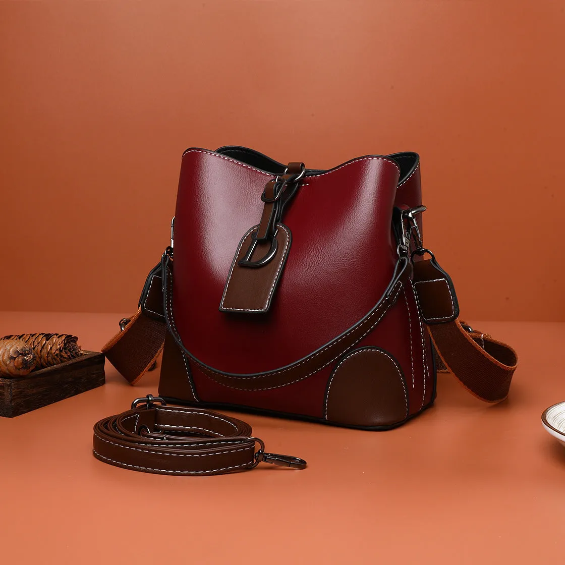 Women's soft PU bucket bag with tassel and contrast colour stitching on a plain background