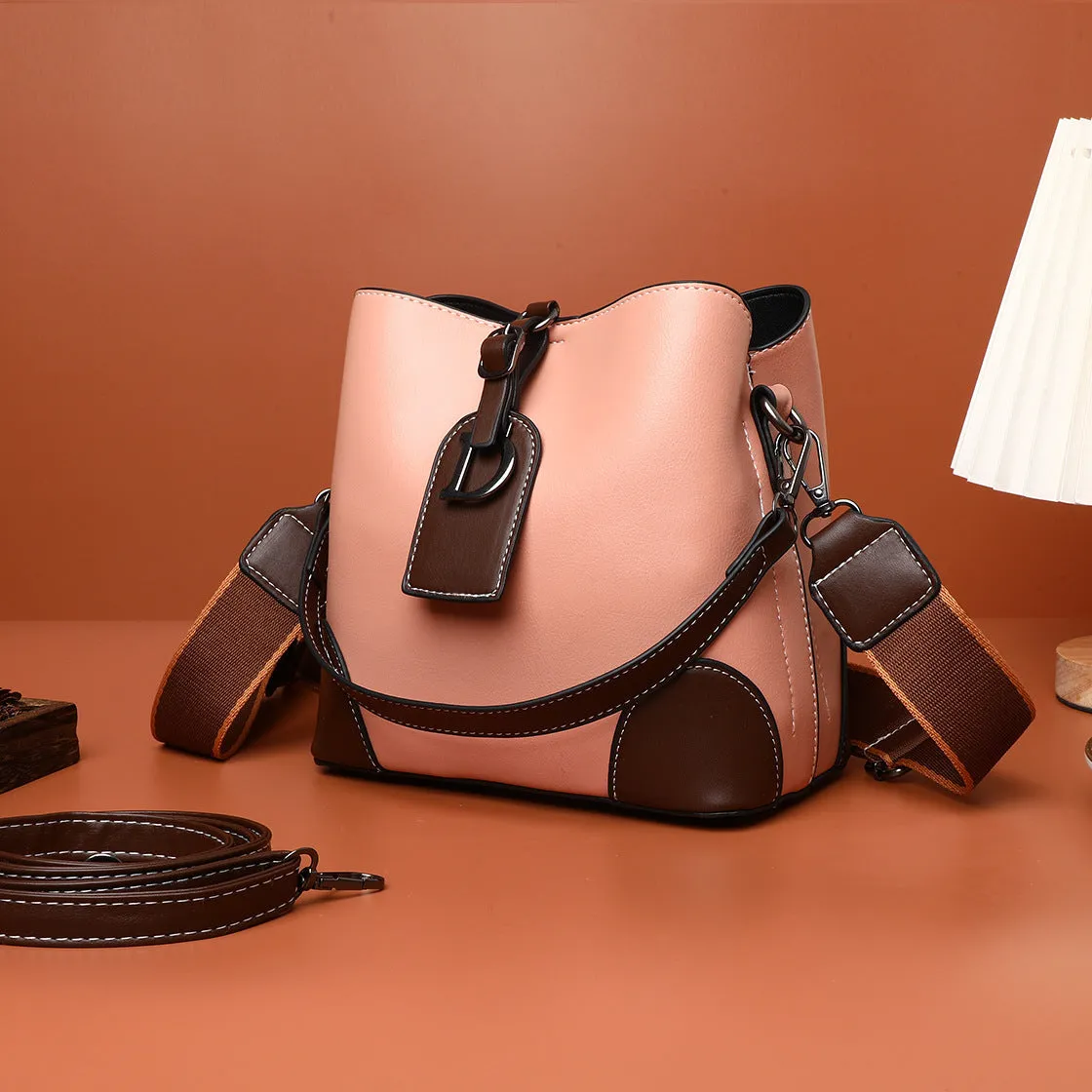 Women's soft PU bucket bag with tassel and contrast colour stitching on a plain background