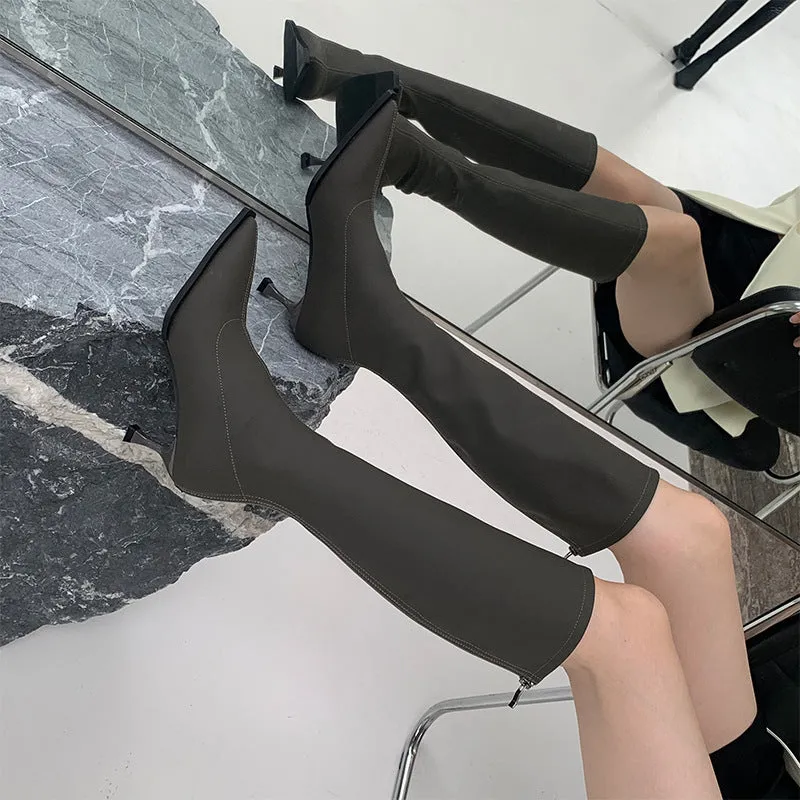 Women's black pointed toe below knee stiletto heel boots with a back zipper on display.