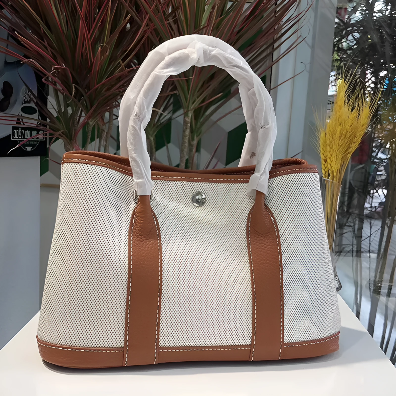 Women's canvas crossbody tote bag with leather trim in bucket shape showing internal organisation pockets.