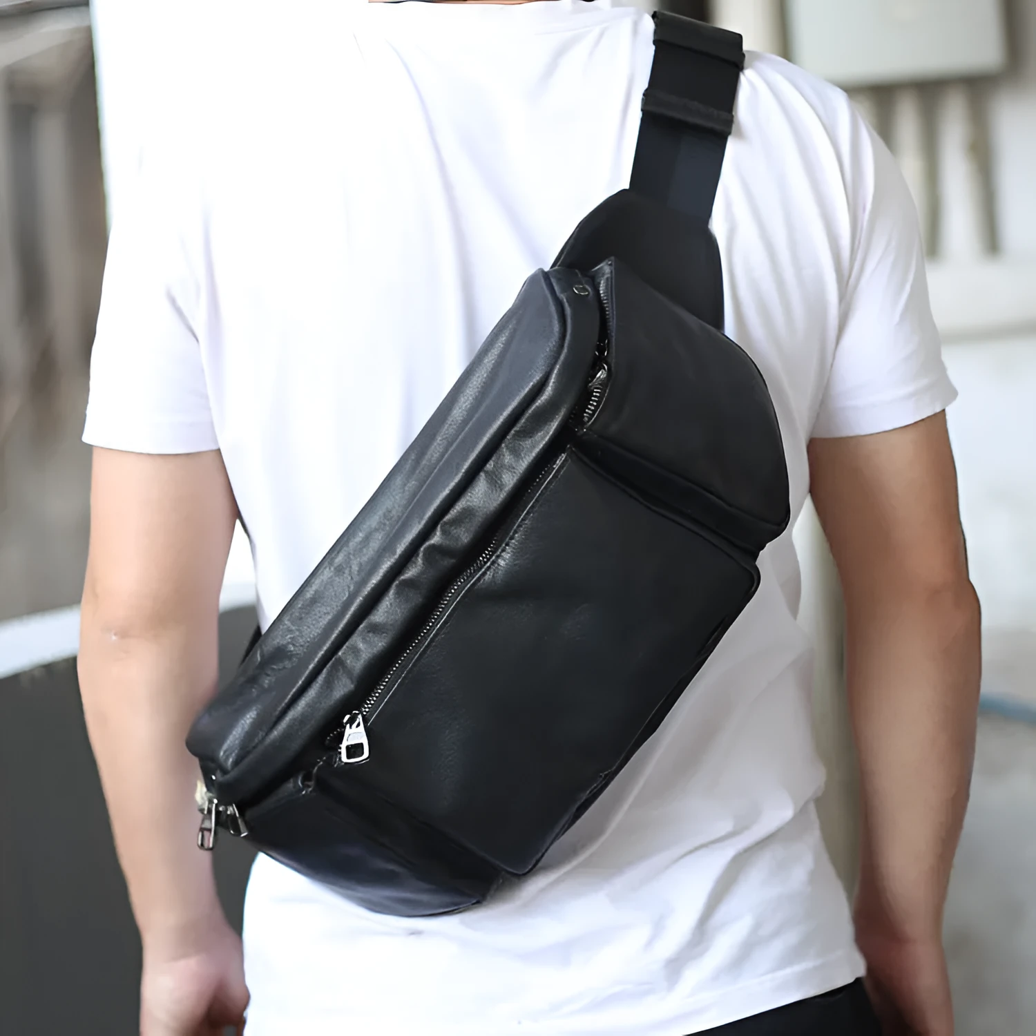 Black cowhide leather messenger bag with large capacity, oval shape, and zipper closure – worn over the shoulder as a crossbody bag