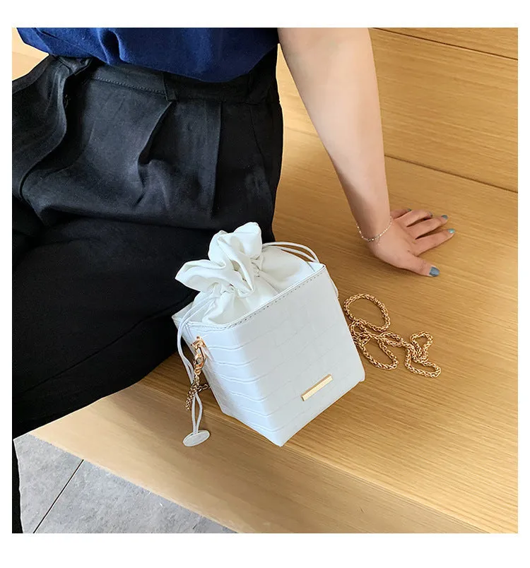 Small black women's chain-strap messenger shoulder bag with a bucket shape and zip opening.