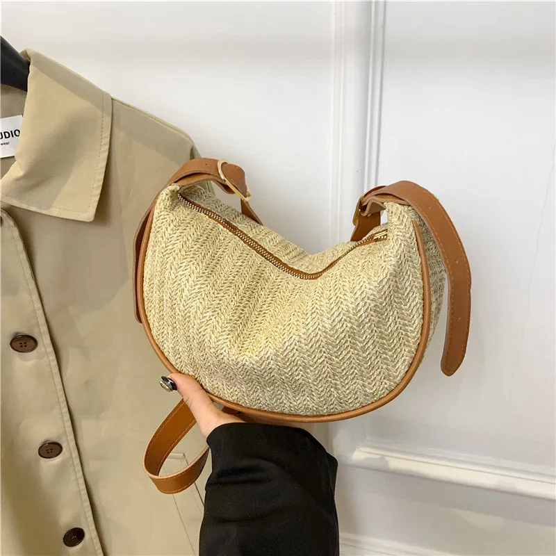 Women's straw woven crossbody bag showing woven texture and adjustable strap with internal phone and document pockets