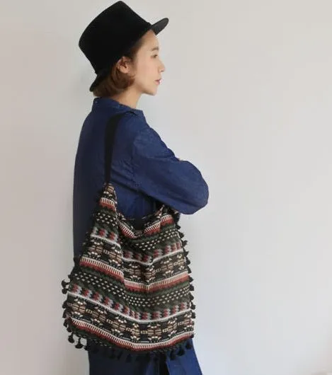 Green geometric tribal tasselled tote bag with oval shape, open top, and two handles, shown on a flat surface