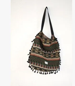 Green geometric tribal tasselled tote bag with oval shape, open top, and two handles, shown on a flat surface