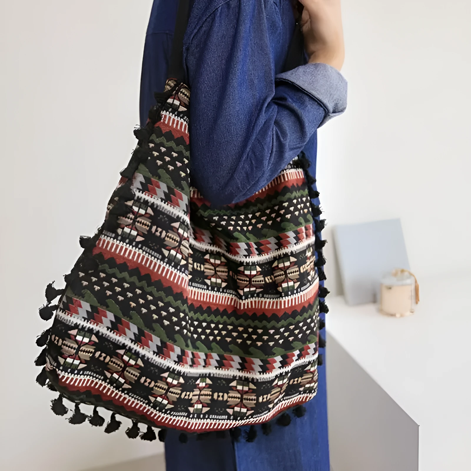 Green geometric tribal tasselled tote bag with oval shape, open top, and two handles, shown on a flat surface