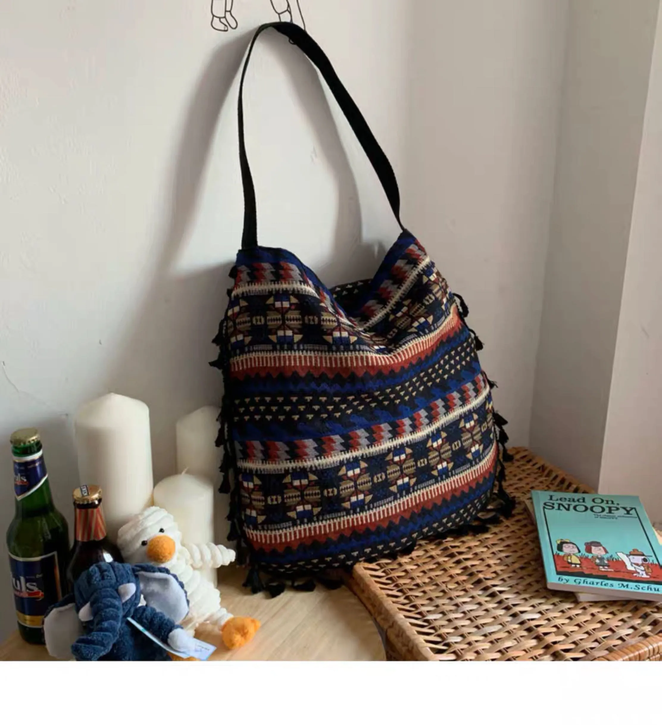 Green geometric tribal tasselled tote bag with oval shape, open top, and two handles, shown on a flat surface