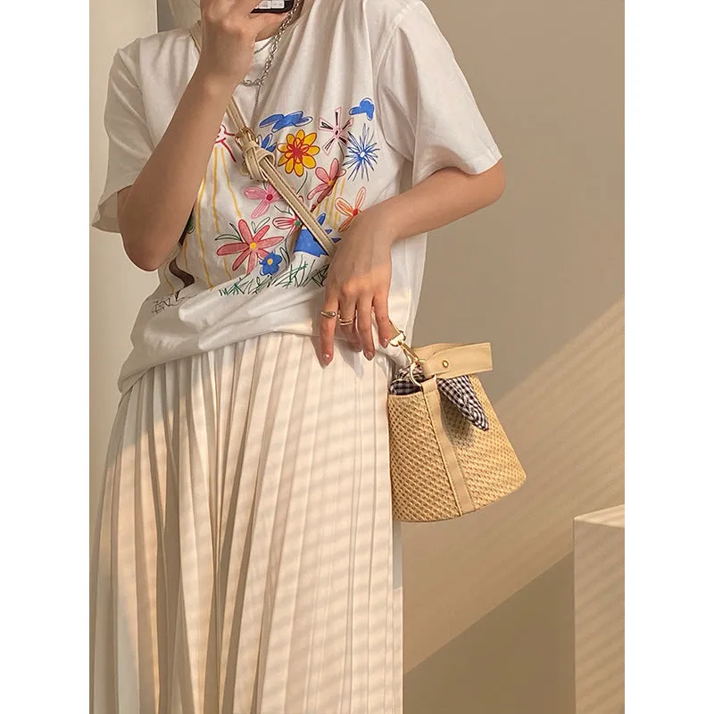 Women's medium beige PU bucket straw bag with open top and messenger strap on neutral background