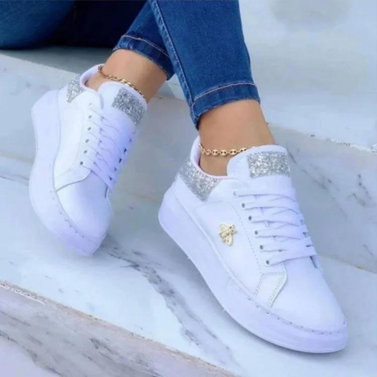 White low-top platform sneakers with lace-up closure and rubber sole on a light background