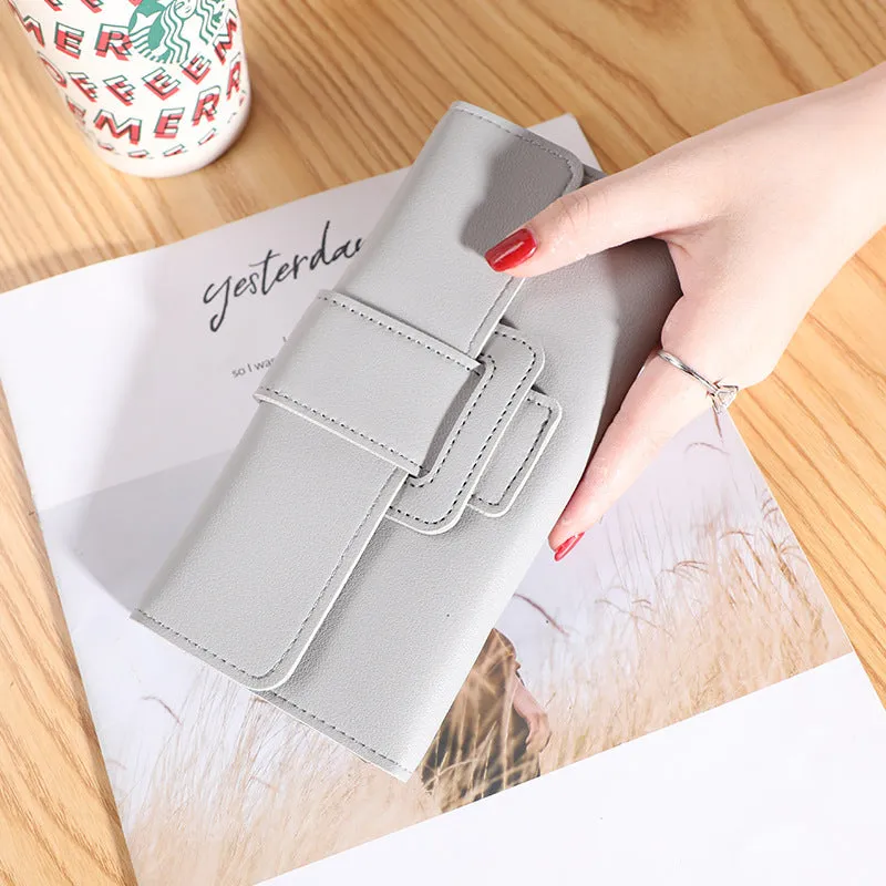 Women's long tri-fold wallet in light grey PU leather with sewing thread detail, open to show multiple card slots and cash compartments.