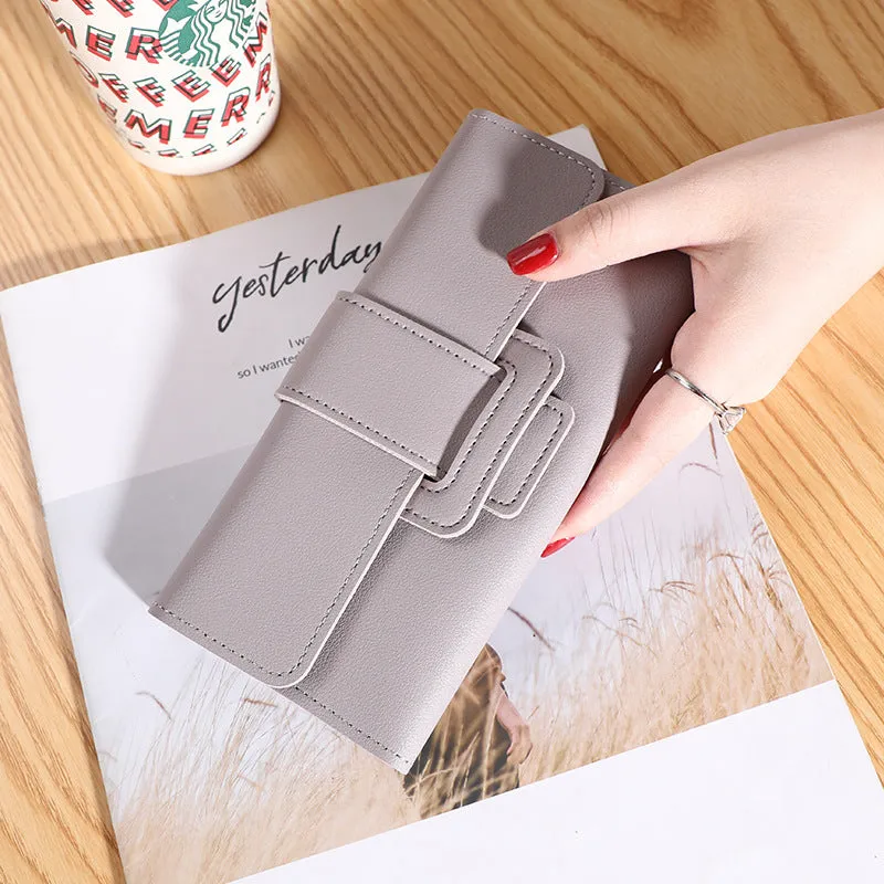 Women's long tri-fold wallet in light grey PU leather with sewing thread detail, open to show multiple card slots and cash compartments.