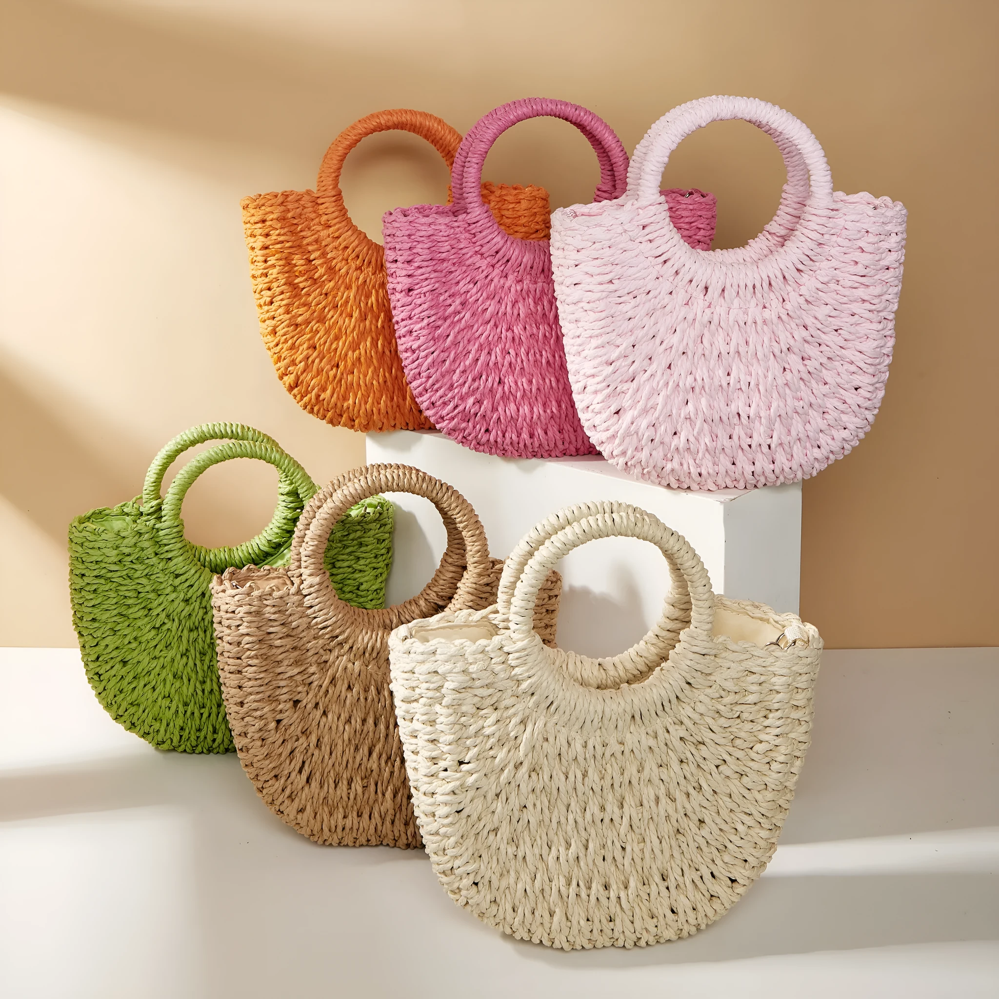 Woven straw beach bag in beige, peach skin lining, crossbody style, 24cm height, on a sandy beach
