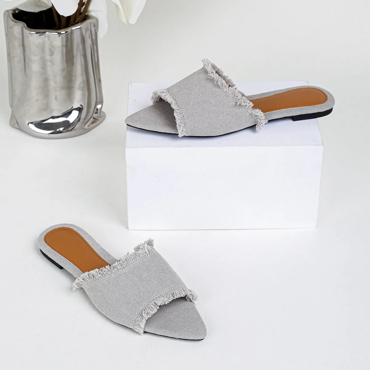 Women's flat denim slippers with a tassel detail in apricot colour on a white background