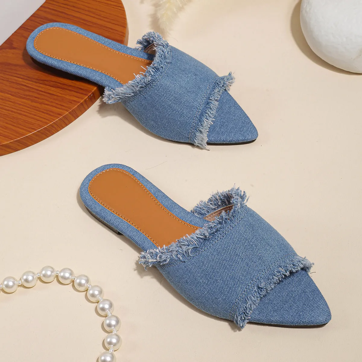 Women's flat denim slippers with a tassel detail in apricot colour on a white background