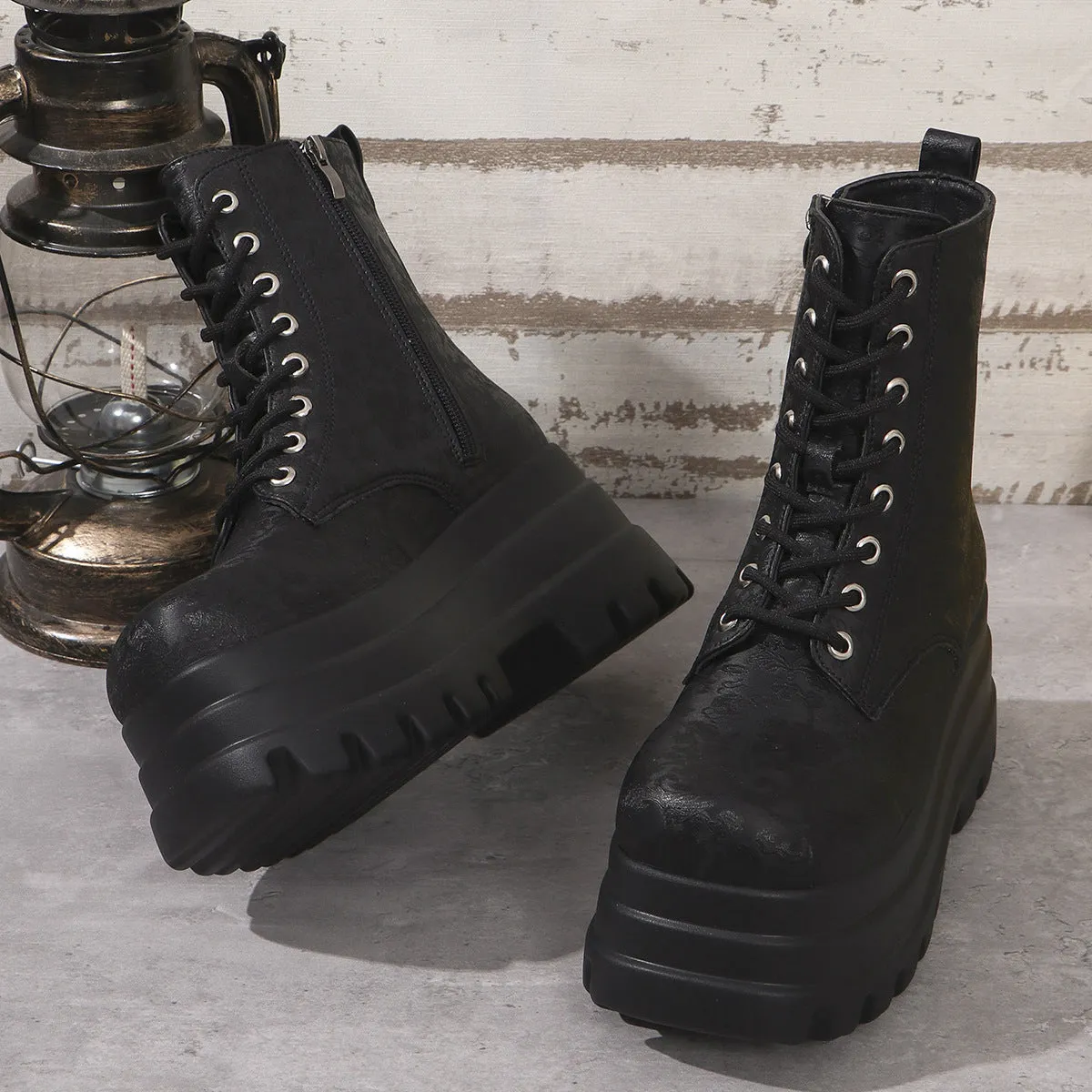 Women's black platform Martin boots with patchwork detail and side zip on a white background.