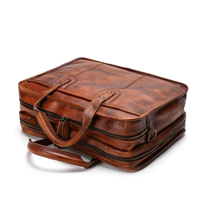 Men's vintage brown leather briefcase open to show internal laptop and camera pockets.