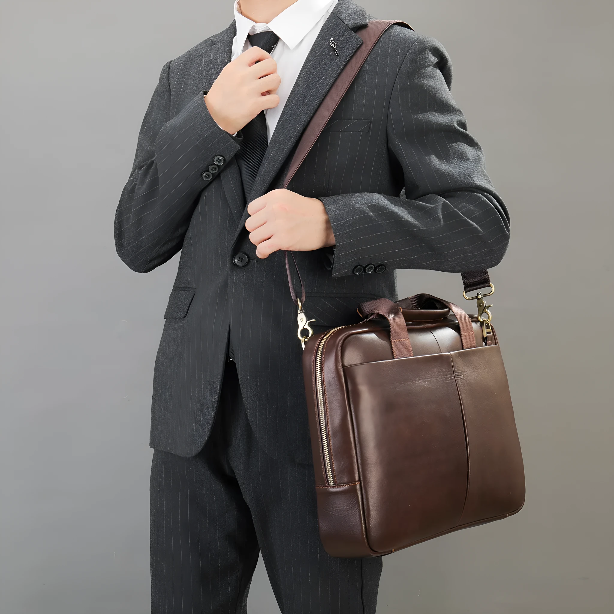 Black cowhide leather one shoulder computer handbag with sewing thread detail on a white background